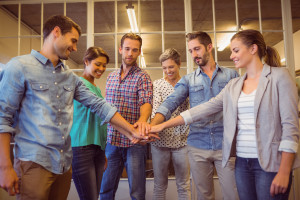 Creative business team putting hands together at the office